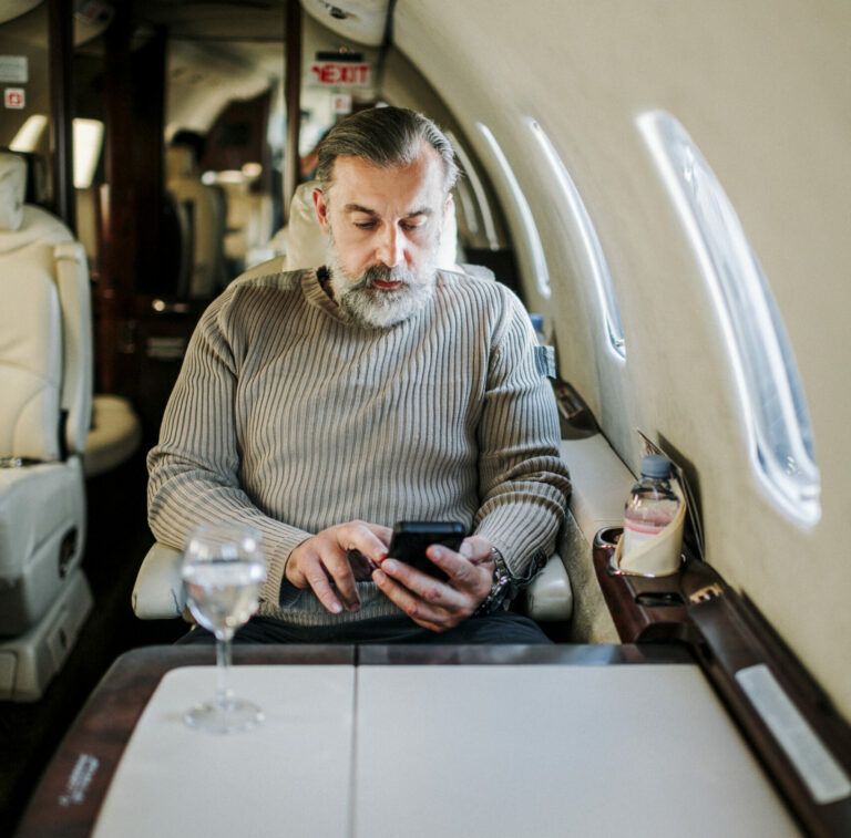 An image of a man paying bill with the Sniip mobile bill payments app flying business class on points.
